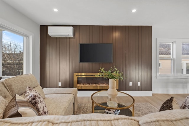 living room featuring hardwood / wood-style flooring, an AC wall unit, and wooden walls