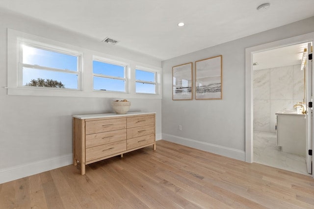 bedroom featuring light wood-type flooring, sink, and ensuite bath