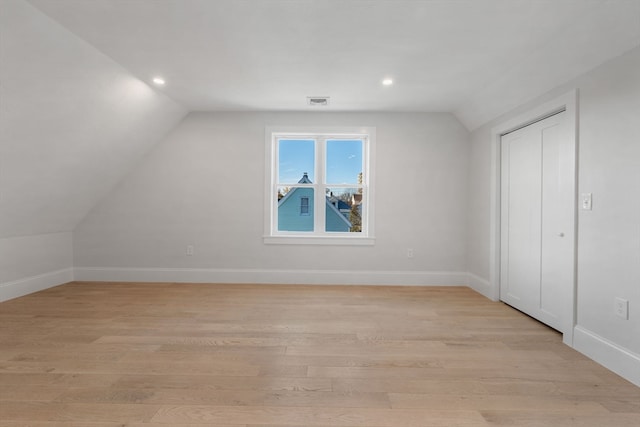 additional living space with light hardwood / wood-style floors and lofted ceiling