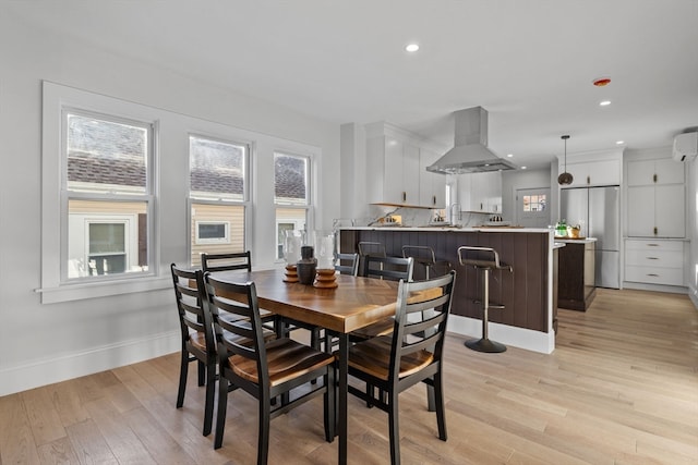 dining room featuring an AC wall unit, sink, and light hardwood / wood-style flooring