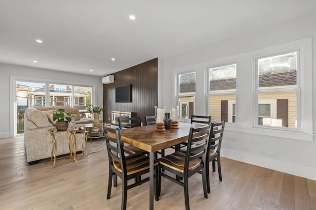 dining room featuring a wall mounted AC and light hardwood / wood-style floors