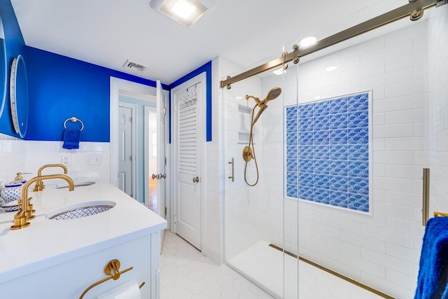 bathroom with tile walls, tile patterned flooring, a shower with door, and vanity