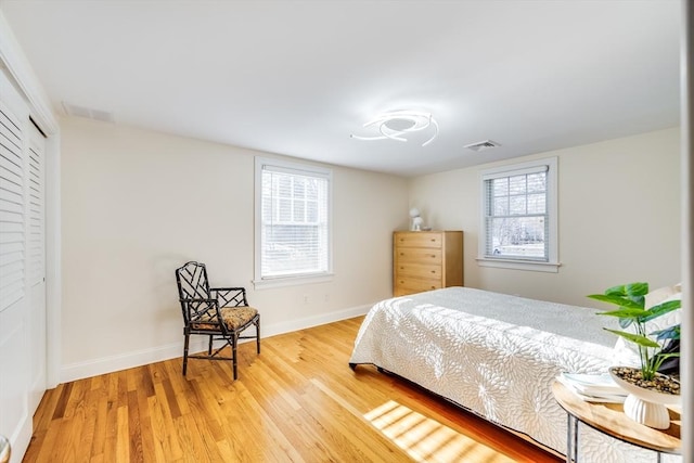 bedroom featuring a closet, multiple windows, and hardwood / wood-style flooring