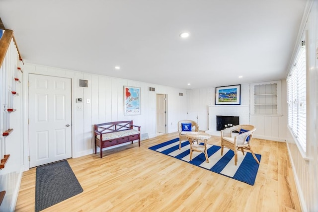 exercise area with light hardwood / wood-style flooring, plenty of natural light, built in shelves, and a fireplace