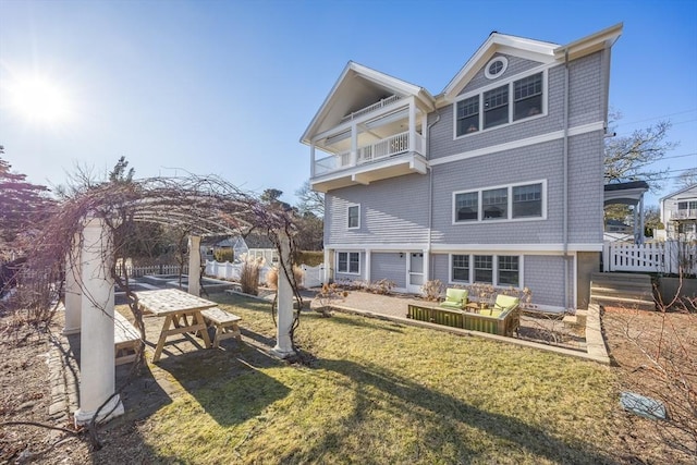 rear view of property featuring a balcony and a lawn