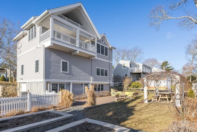 back of house with a balcony, a lawn, and a gazebo