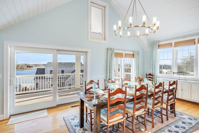 dining area with light hardwood / wood-style flooring, an inviting chandelier, and high vaulted ceiling