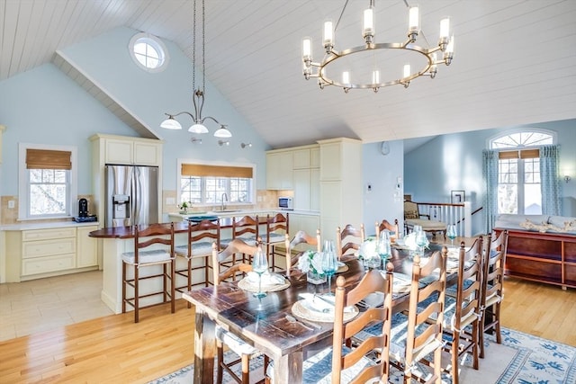 dining room featuring a notable chandelier, high vaulted ceiling, light hardwood / wood-style floors, and sink