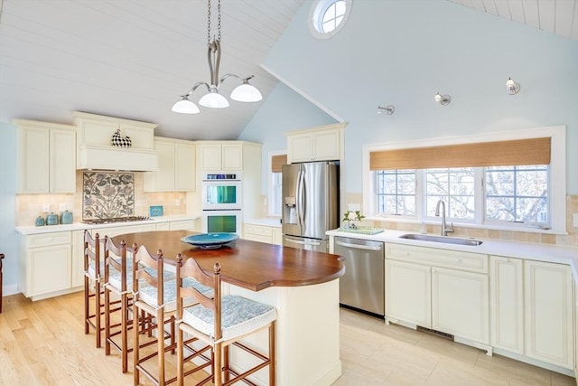 kitchen featuring stainless steel appliances, tasteful backsplash, a kitchen island, high vaulted ceiling, and sink