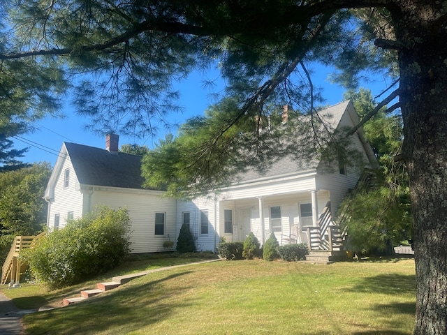 rear view of property featuring a porch and a lawn