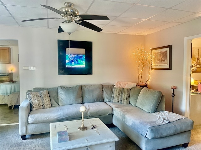 living room with a drop ceiling, ceiling fan, and carpet flooring