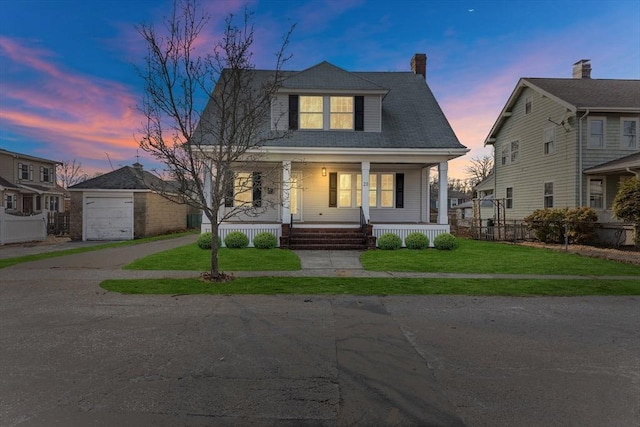 view of front of home with an outbuilding, a yard, a porch, a garage, and driveway