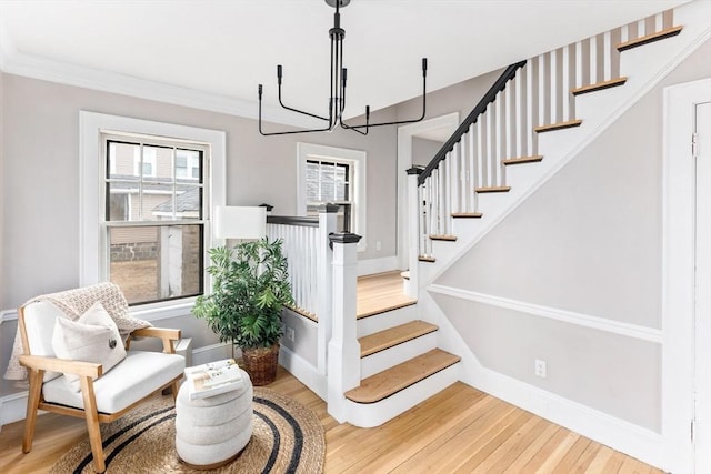 stairway with ornamental molding, wood finished floors, and baseboards