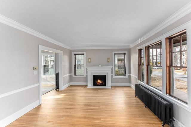 unfurnished living room featuring radiator heating unit, a fireplace with flush hearth, light wood-style flooring, and baseboards