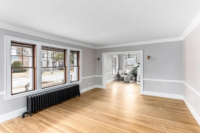 empty room featuring ornamental molding, light wood-type flooring, radiator, and baseboards