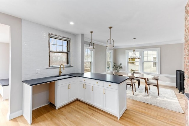 kitchen with dark countertops, light wood-style floors, white cabinetry, and a sink