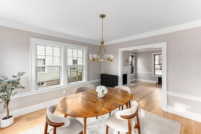 dining space with baseboards, light wood-type flooring, radiator heating unit, an inviting chandelier, and crown molding