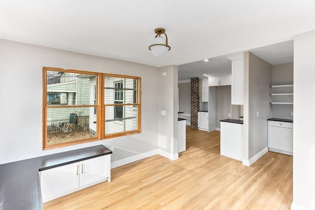 unfurnished dining area with light wood-type flooring and baseboards