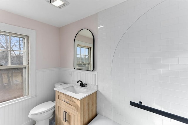 bathroom featuring a wainscoted wall, toilet, vanity, and visible vents