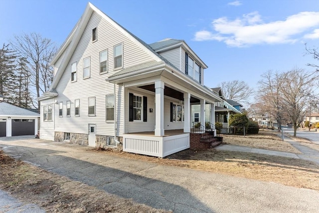 view of front of house with a garage, a porch, and an outbuilding