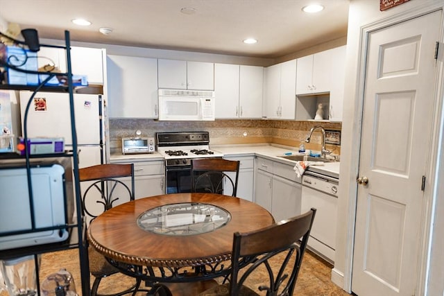 kitchen featuring sink, white appliances, white cabinets, and backsplash