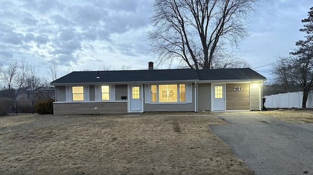 ranch-style home with aphalt driveway and fence