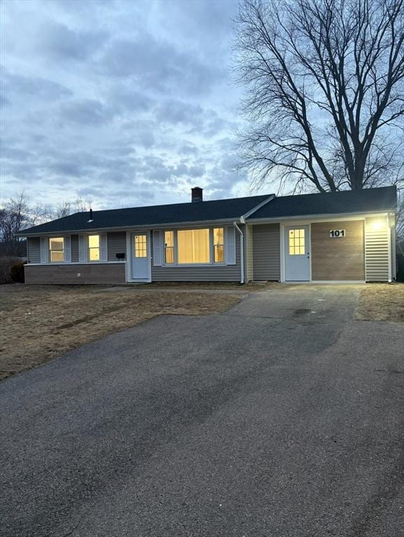 single story home with aphalt driveway and a chimney