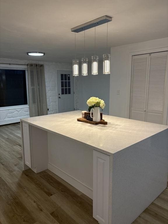 kitchen with a large island, white cabinetry, dark wood-type flooring, and decorative light fixtures