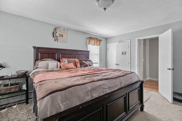 bedroom with light colored carpet and a textured ceiling
