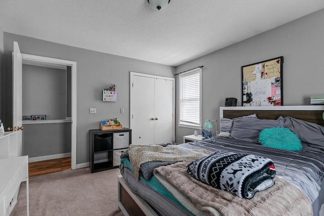 carpeted bedroom with a closet, a textured ceiling, and baseboards