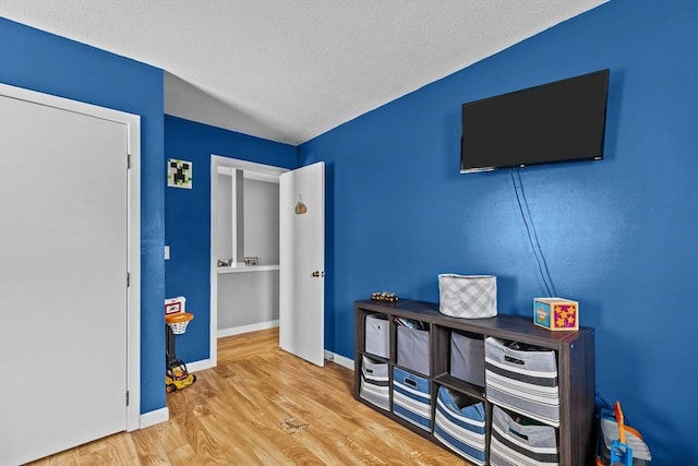bedroom featuring wood finished floors, baseboards, and a textured ceiling