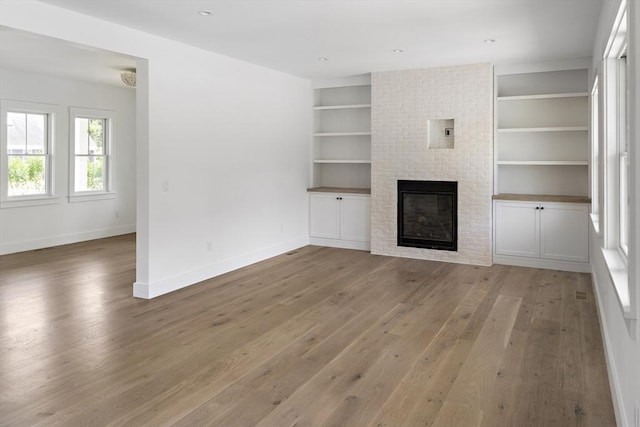 30 Franklin Ave, Oak Bluffs, MA 02557 - unfurnished living room with light wood-type flooring, baseboards, a brick fireplace, and built in shelves