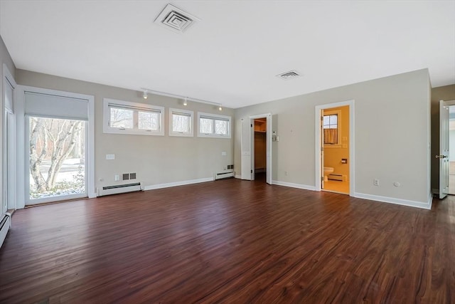 unfurnished living room featuring baseboard heating, a wealth of natural light, and dark hardwood / wood-style floors