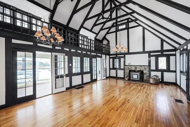 unfurnished living room featuring hardwood / wood-style floors, high vaulted ceiling, and a notable chandelier