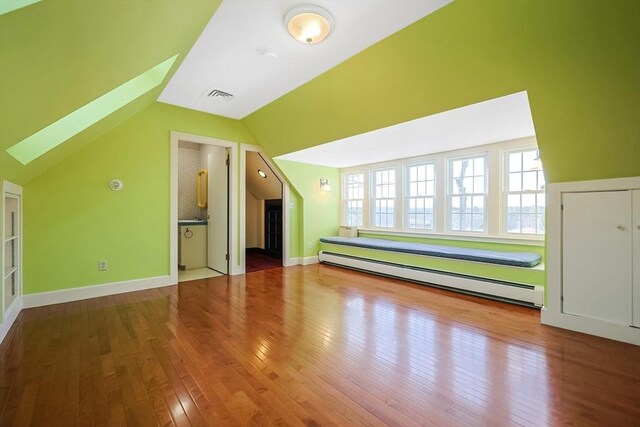 additional living space featuring baseboard heating, vaulted ceiling, and hardwood / wood-style flooring