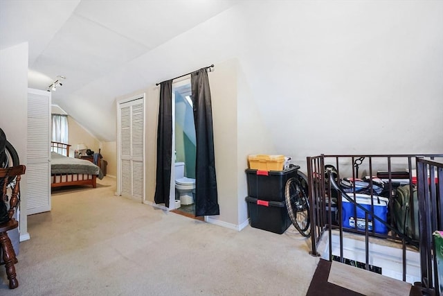 carpeted bedroom featuring ensuite bathroom and vaulted ceiling