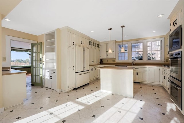 kitchen featuring built in appliances, a wealth of natural light, a kitchen island, and decorative light fixtures