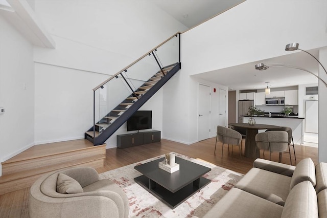 living area with light wood-style floors, stairs, and baseboards