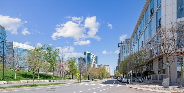 view of street featuring curbs, traffic signs, a city view, and sidewalks