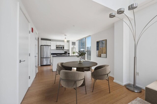 dining area with baseboards and light wood-style flooring