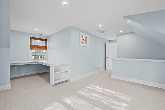 additional living space featuring lofted ceiling, built in desk, and light carpet