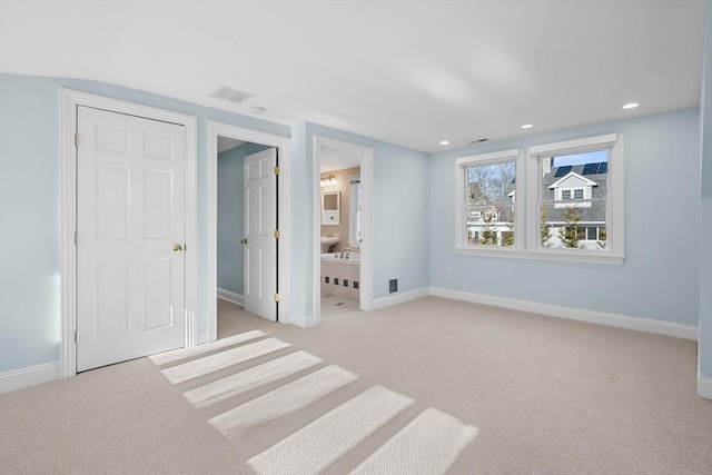 unfurnished bedroom featuring light carpet and ensuite bath