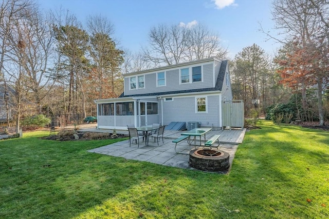 rear view of property featuring a yard, a fire pit, a sunroom, and a patio