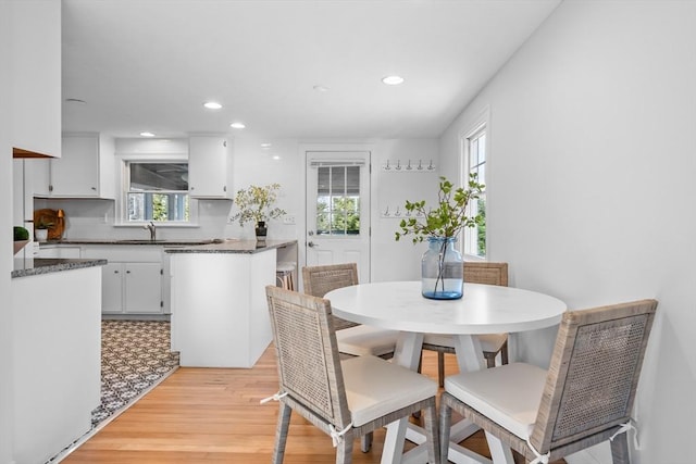 dining room featuring sink, light hardwood / wood-style floors, and a healthy amount of sunlight