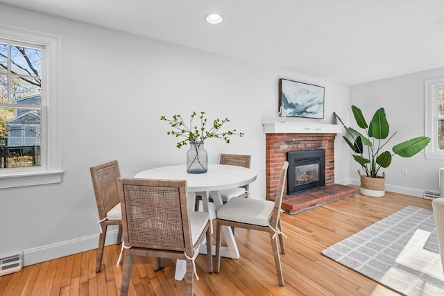 dining area with wood-type flooring, a fireplace, and a baseboard radiator