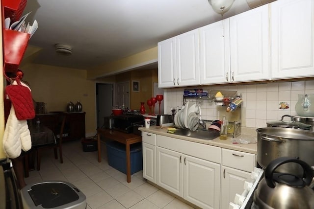 kitchen with white cabinetry, light tile patterned floors, decorative backsplash, and sink