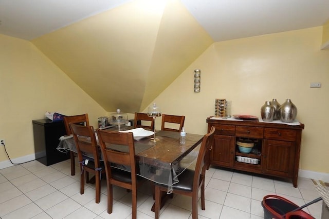 dining area with light tile patterned flooring and vaulted ceiling