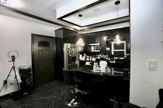 bar featuring pendant lighting, a raised ceiling, and appliances with stainless steel finishes