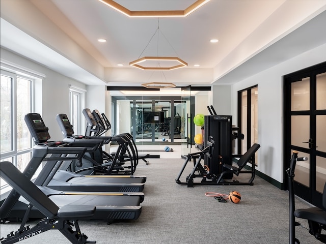 exercise room with carpet flooring and a tray ceiling