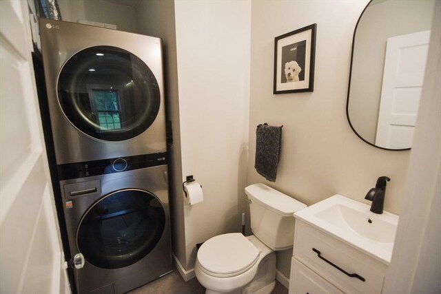 bathroom featuring stacked washer / dryer, vanity, and toilet